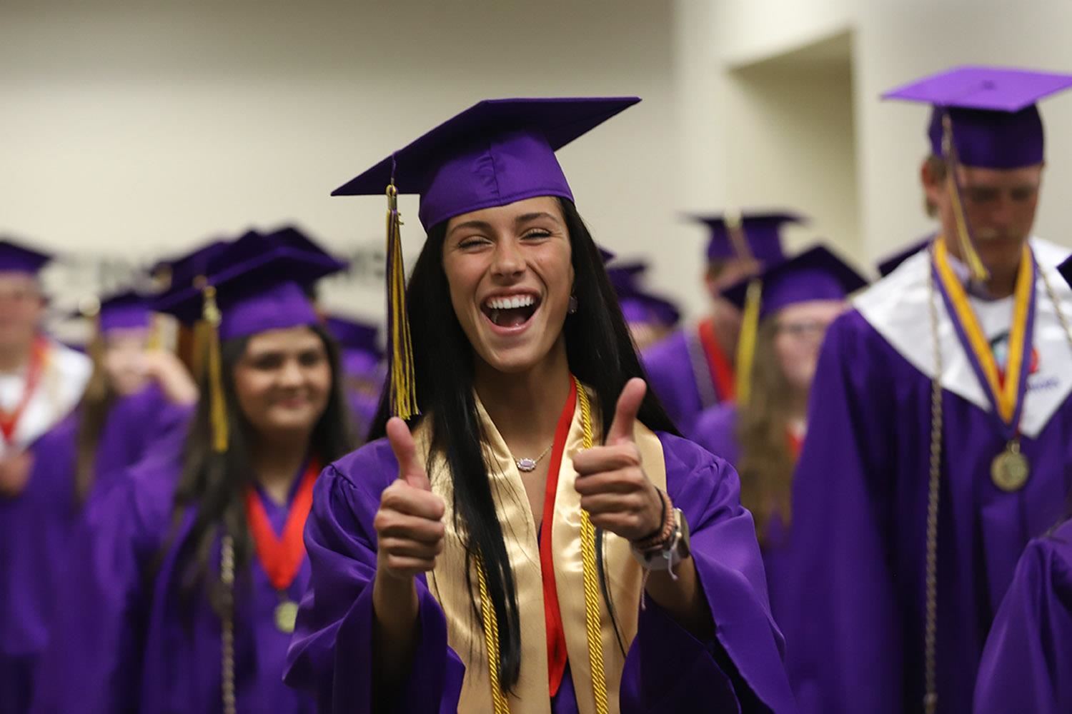 Smiling GISH grad holding thumbs up and wearing purple graduation regalia